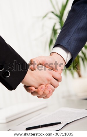 Photo of handshake of business partners after striking deal on background of signed documents