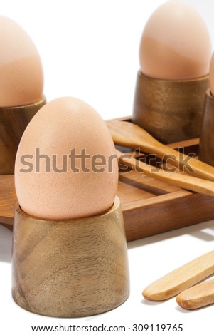 Boiled eggs in the wooden holder on the white background.