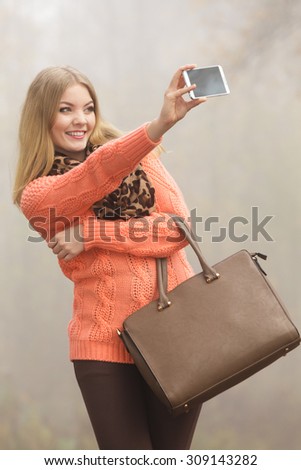 Happy fashion woman in fall autumn park taking selfie self photo picture. Pretty joyful girl photographing.
