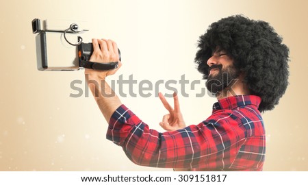 Afro man filming over ocher background