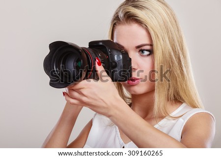 Photographer girl shooting images. Attractive blonde woman taking photo with camera.
