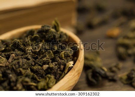 Oolong tea in wooden spoon on a background of old vintage books. Menu, recipe