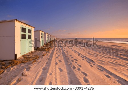 A row of beach huts on a beach on the island of Texel in The Netherlands. Photographed at sunset.