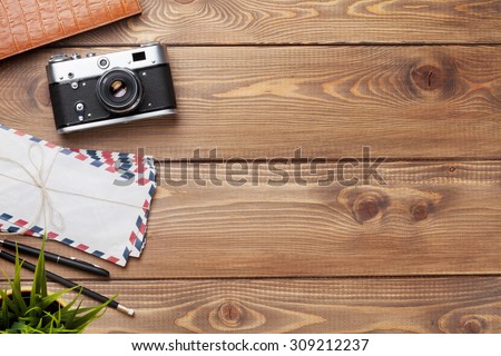 Camera and supplies on office wooden desk table. Top view with copy space