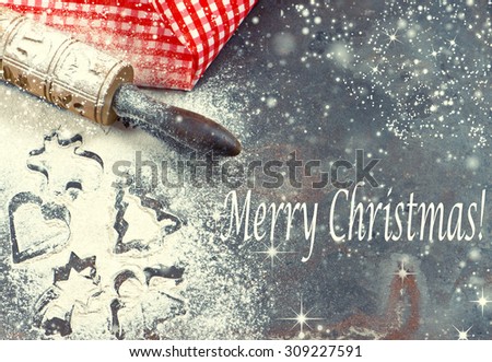 Flour, rolling pin and red napkin. Christmas holidays concept. Retro style toned picture with sample text Merry Christmas! and snow effect