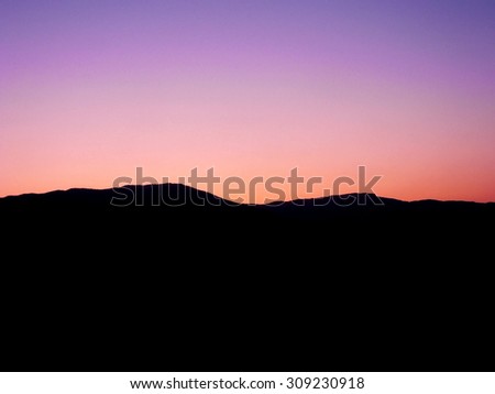 Black silhouette of mountains on background of pink sunset