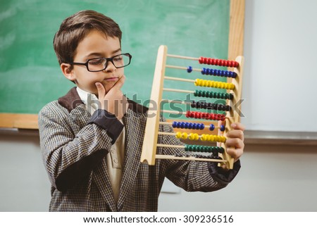 Pupil dressed up as teacher holding abacus in a classroom Royalty-Free Stock Photo #309236516