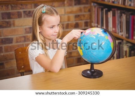 Students pointing to places on a globe at the elementary school