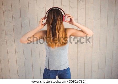 Pretty hipster listening to music on wooden planks background