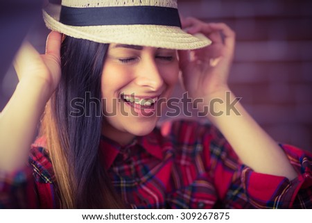 Beautiful hipster laughing at camera on red brick background