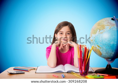 Cute pupil working at her desk against blue background with vignette