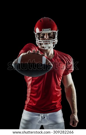 American football player showing ball on black background