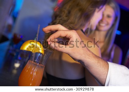 Man Drugging Woman's Drink In Bar Royalty-Free Stock Photo #30929878