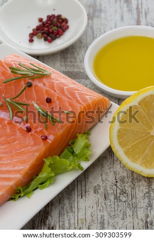Delicious portion of fresh salmon fillet with aromatic herbs and spices over wooden vintage background