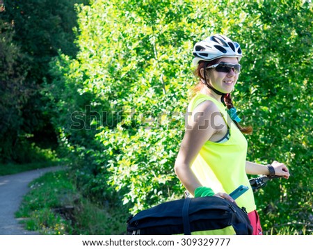 Woman riding a bike on the forest trail in sunny day