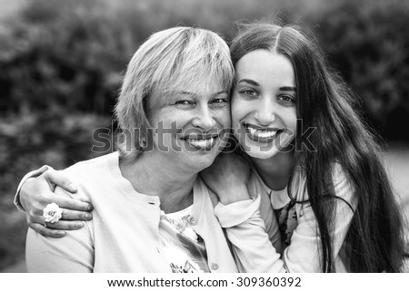 Mother with her daughter smiling and hugging dressed in yellow in the park. Black and white photo