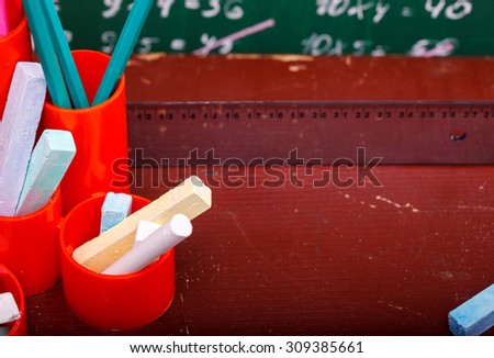 Colorful pencils of red yellow orange violet purple pink green and blue in stationary cup ruler and chalk on brown desk school background copyspace, horizontal picture