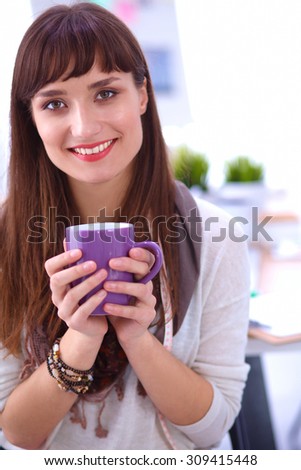 Modern young fashion designer with cup at studio