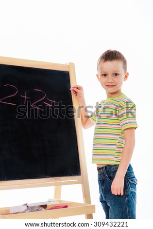 Nice boy  standing with chalk and solving math