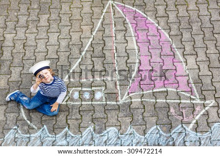 Adorable little kid boy playing with colorful chalks and painting ship or boat picture. Creative leisure for children outdoors in summer, Family, happy childhood,  kids concept