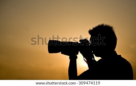 Silhouette of a photographer holding a telephoto lens