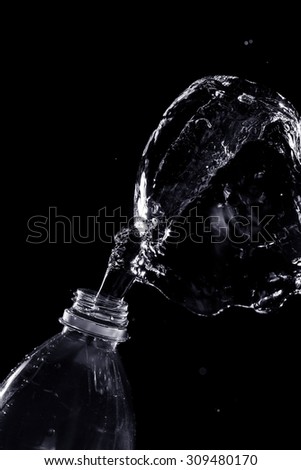 Abstract water jet crashes on a black background from a plastic bottle. Texture. Design elements. Spray. Refreshing.