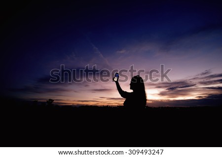 Silhouette of woman take a photo at sunset