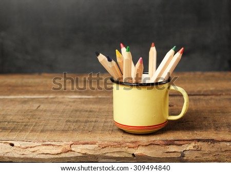 Still life, business, education concept. Pencils in a mug on a wooden table and chalkboard. Selective focus, copy space, school background