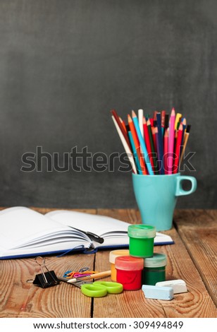 Still life, business, education concept. School supplies and open notebook on a wooden table with chalkboard. Selective focus, copy space, school background