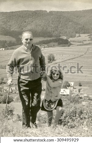 Vintage photo of father and daughter walking in mountains, 1950's