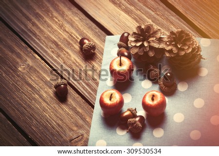 Little apples and pine cones on wooden table.