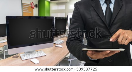 Businessman using the tablet on empty computer room background, education and business concept