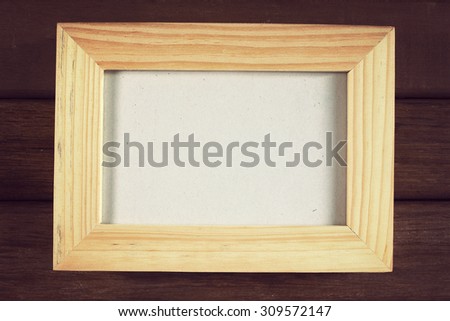 Blank picture frame on old wooden wall. Vintage effect.