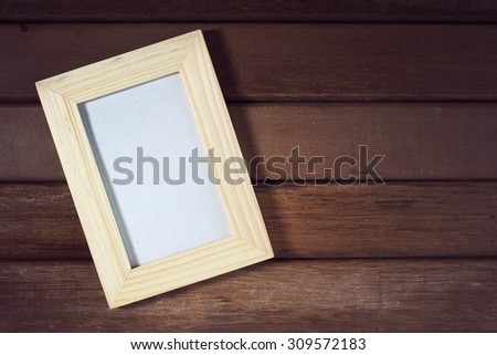 Blank picture frame on old wooden wall. Vintage effect.