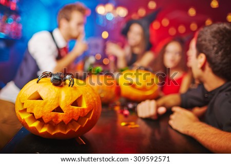 Jack-o-lantern on bar counter and friends on background