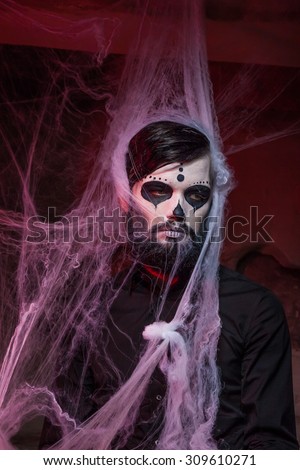 Halloween concept with young man in day of the dead mask face art.