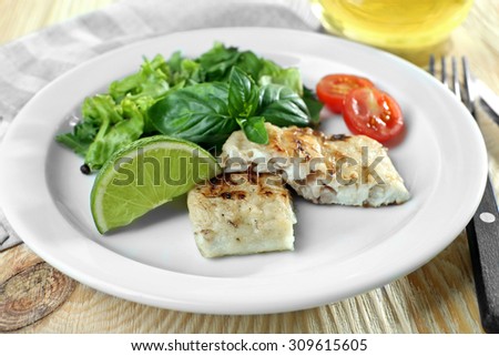 Dish of fish fillet with salad and lime on table close up