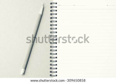 Notebook with pencil on wood background- vintage filter