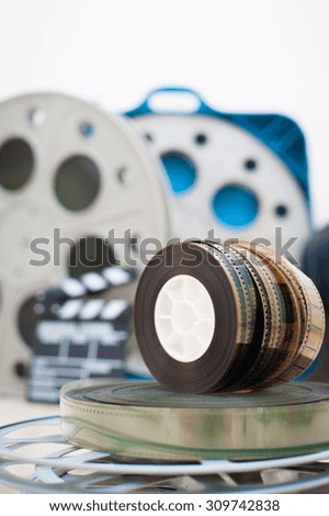Heap of old 35 mm movie reels with out of focus clapper and boxes in background, vertical frame