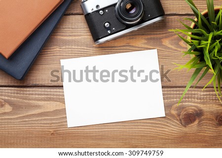 Blank photo frame or card, camera and supplies on office wooden desk table. Top view with copy space
