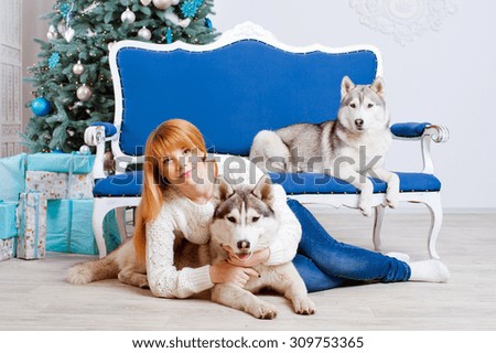 Young beautiful red hair woman in a Christmas setting with dogs. Husky.