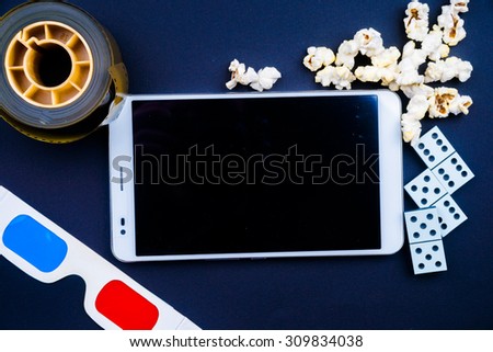 Tablet pc on dark background with attributes of cinema. Visual metaphor for content consumption - films and games on a mobile device.