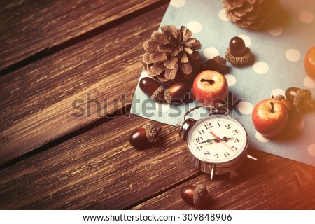 Alarm clock and pine cones on wooden table.