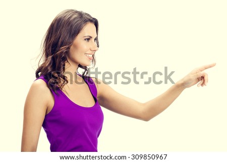 Profile view of happy smiling beautiful young woman in casual smart lilac clothing, showing copyspace, visual imaginary or something, or pressing virual button