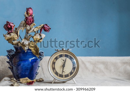 Clock and a vase of flowers on a white background.