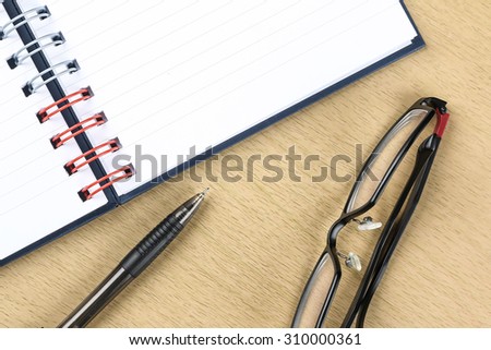pen, glasses and blank opened notebook on the table, business , education