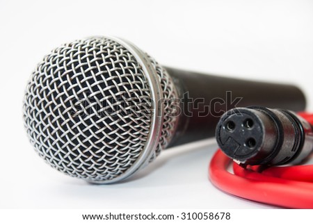 Used vocal microphone with red xlr cable on the white background.