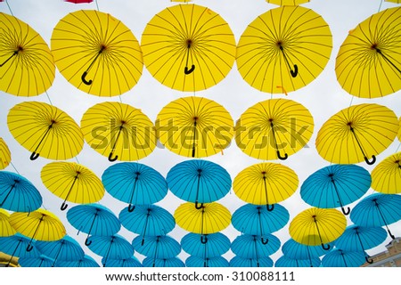 Bright colorful yellow and blue umbrellas against white background 