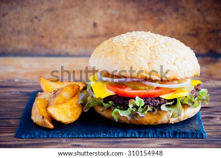 Homemade burger made from fresh vegetables and beef on wooden background