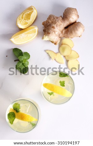 refreshing flavors of lemonade, ginger, and mint in a glass, on white marble top table